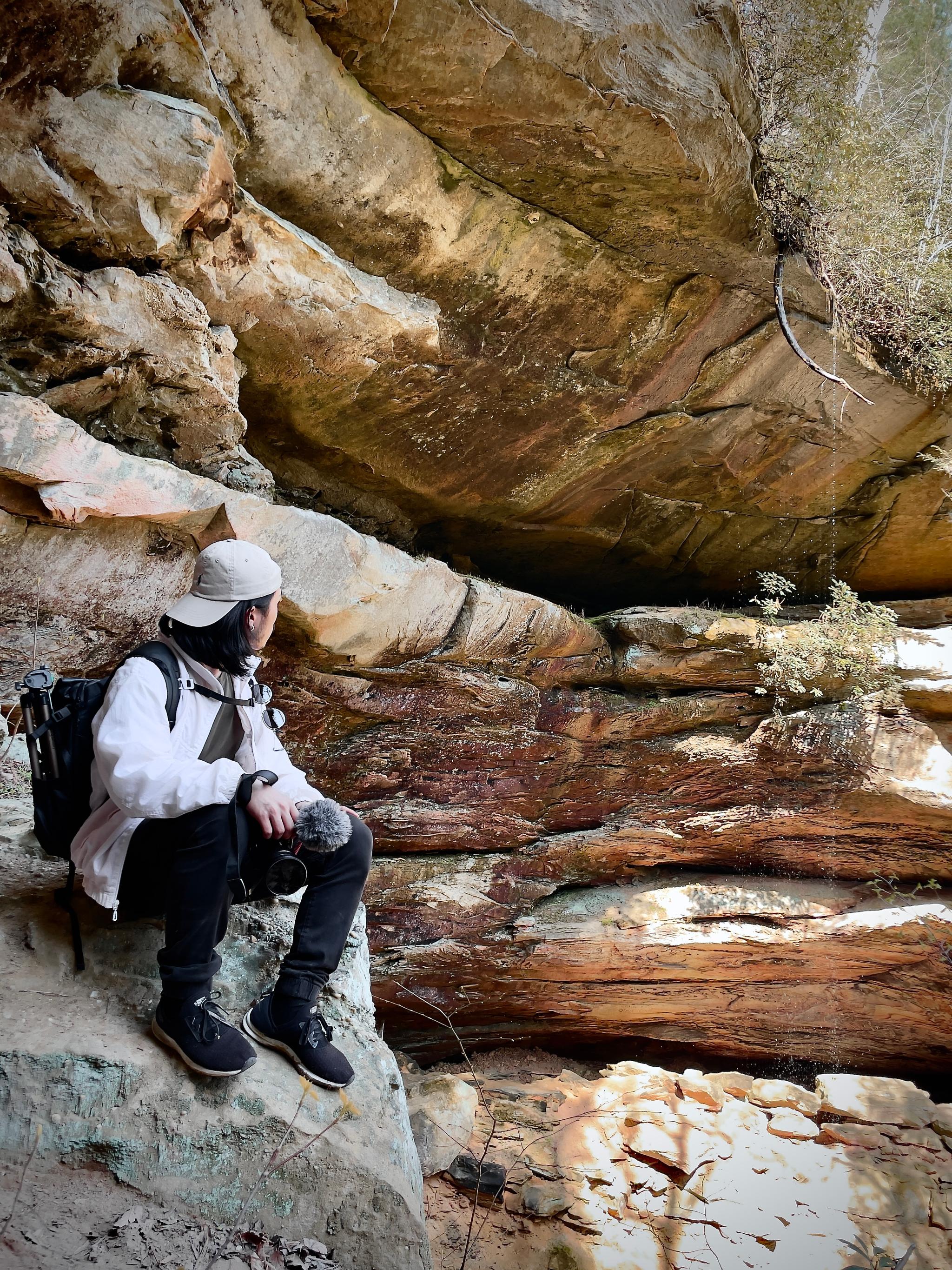 Jaeheon with a camera sitting in a rock